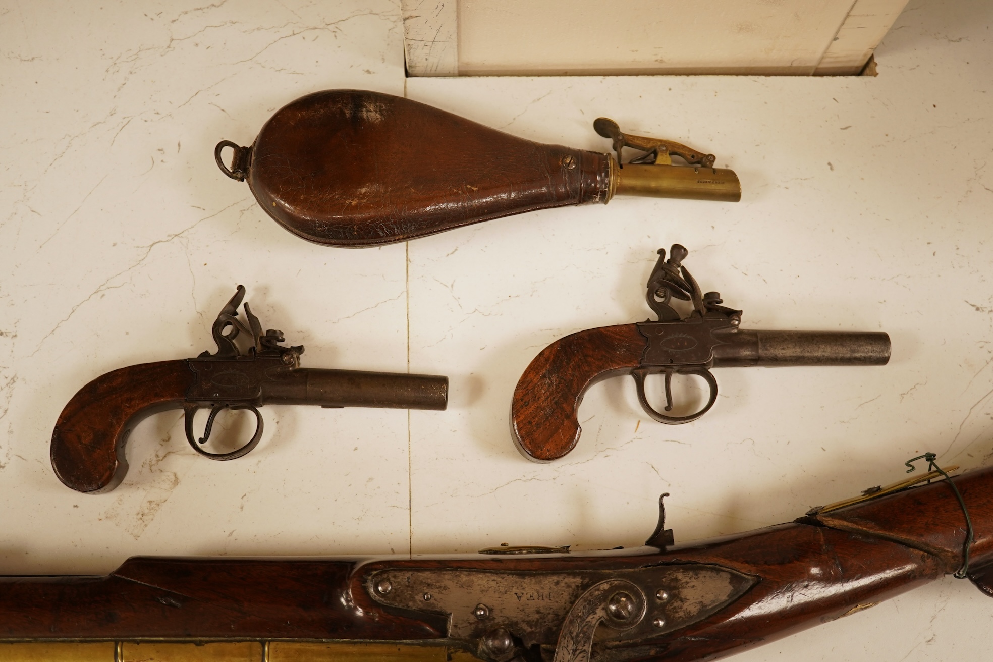 A pair of 19th century pocket pistols, shot flask and a brass musket, 81cm in length